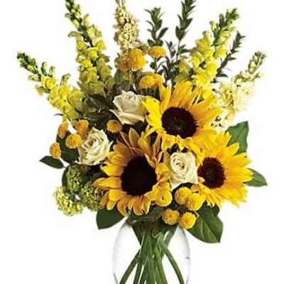 Tall arrangement of yellow sunflowers, white roses, and yellow blooms in a clear glass vase