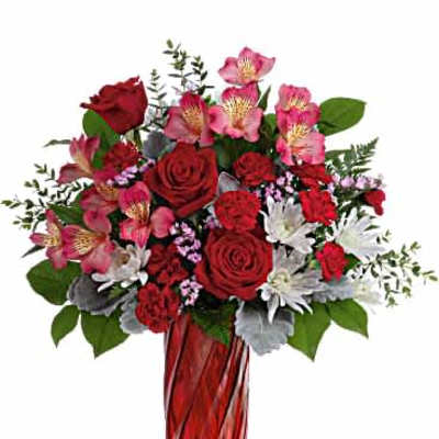 Tall arrangement of red roses, red carnations, pink alstroemeria and white mums in a red glass vase