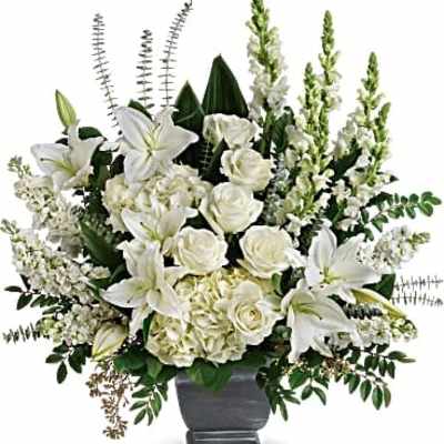 Large all-white arrangement of lilies, roses, hydrangeas and snapdragons in a gray pedestal vase