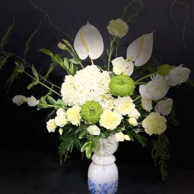 White floral arrangement in a blue-and-white vase with green accents