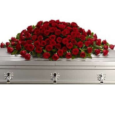 Large spray of red roses arranged across a silver casket.