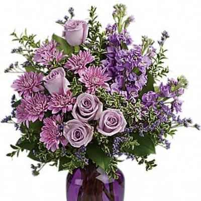 Lavender and purple flower arrangement with roses and mums in a purple glass vase