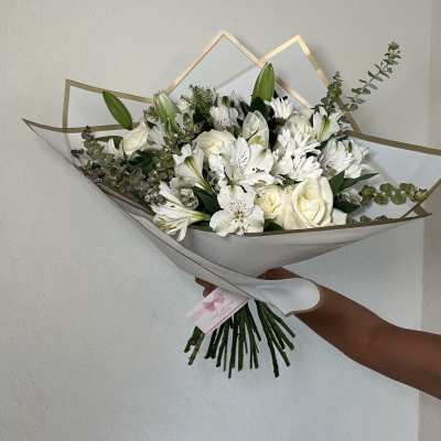 White bouquet of roses, lilies, and daisies wrapped in paper