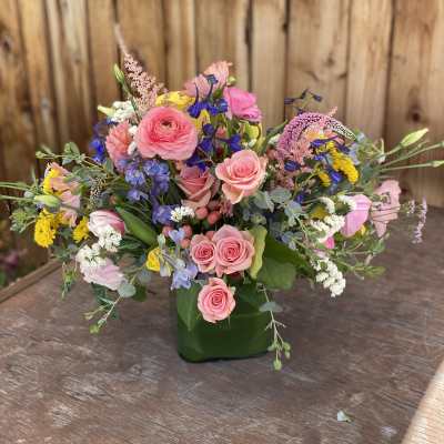 Mixed bouquet of pink roses and colorful wildflowers in a green vase