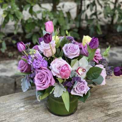 Lavender rose and tulip bouquet in a green glass vase
