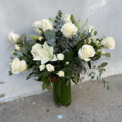 White roses and lilies arranged in a tall green vase