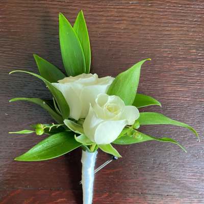 White rose boutonniere with green leaves on a wrapped stem