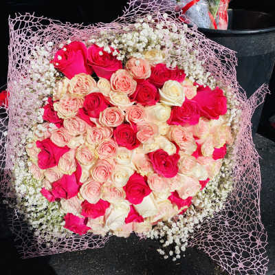 Bouquet of pink and cream roses wrapped in pink mesh