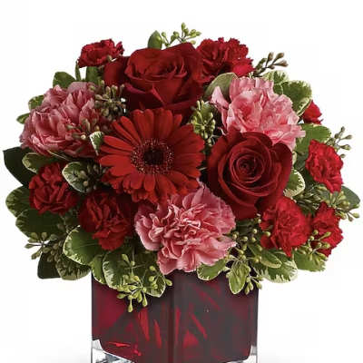 Red and pink floral arrangement in a square glass vase