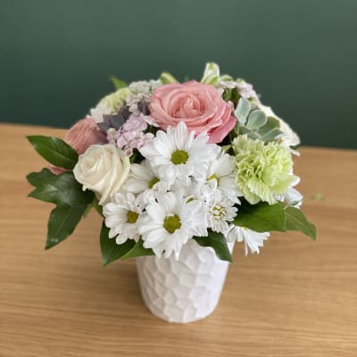 Pink and white flowers arranged in a white vase