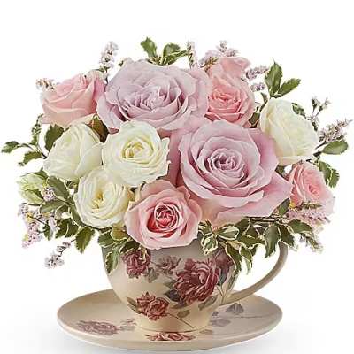 Pink and white roses arranged in a floral teacup with saucer
