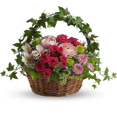 Basket arrangement of pink roses and mixed flowers with ivy arch