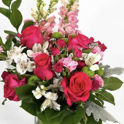 Pink roses and mixed blooms arranged in a clear glass vase