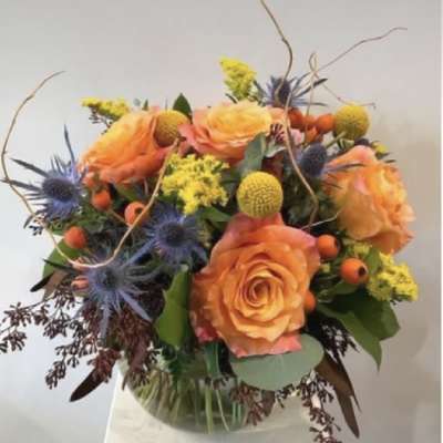 Bouquet of orange roses with blue thistle and yellow accents