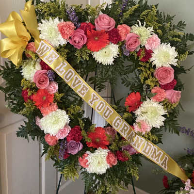 Heart-shaped floral wreath with a yellow ribbon reading "We Love You Grandma"