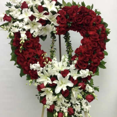 Heart-shaped standing spray of red roses and white lilies on an easel