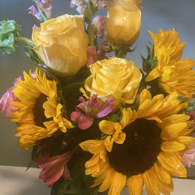Bouquet of yellow roses and sunflowers in a glass vase
