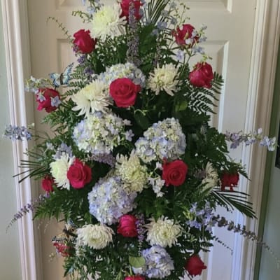 Tall floral standing spray with pink roses, white blooms, and blue hydrangeas