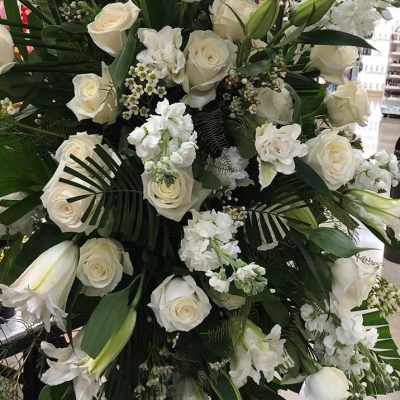 Large white floral standing spray with roses and lilies on an easel