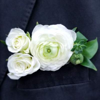 White floral boutonniere pinned to a dark suit jacket