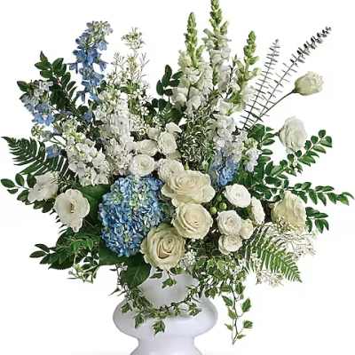 White and blue floral arrangement in a white pedestal vase