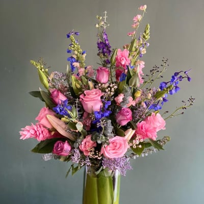 Pink and purple mixed flower arrangement in a tall glass vase