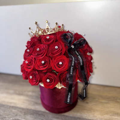 Red rose arrangement in a velvet box with a crown and birthday ribbon