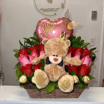Basket arrangement of red and pink roses with a teddy bear and heart balloon