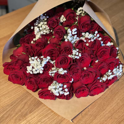 Bouquet of red roses with white baby's breath in brown paper