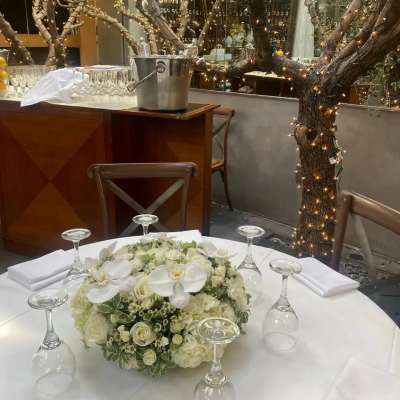 White floral centerpiece on a round table with upside-down wine glasses