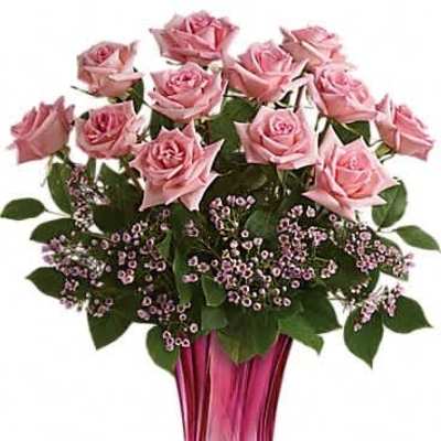 Arrangement of pink roses with tiny pink blossoms in a tall pink glass vase