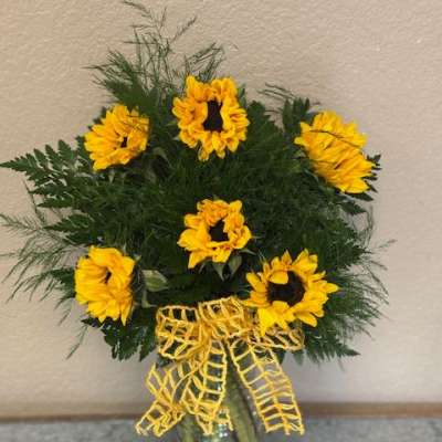 Sunflower arrangement in a glass vase with a yellow ribbon
