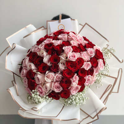 Large bouquet of red and pink roses wrapped in white paper