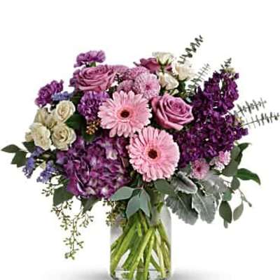 Mixed bouquet of pink and purple flowers arranged in a clear glass vase