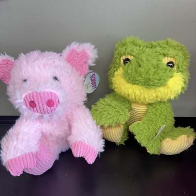 Two plush stuffed animals, a pink pig and a green frog, sit side by side.