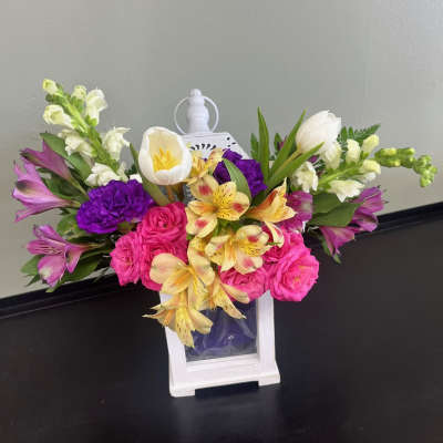 Colorful bouquet in a white lantern vase with pink, purple, yellow, and white flowers