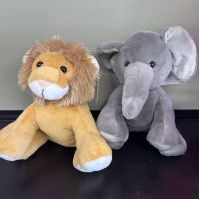 Two plush stuffed animals, a lion and an elephant, sit side by side.
