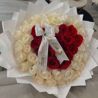 Bouquet of red and white roses wrapped in white paper with a satin bow