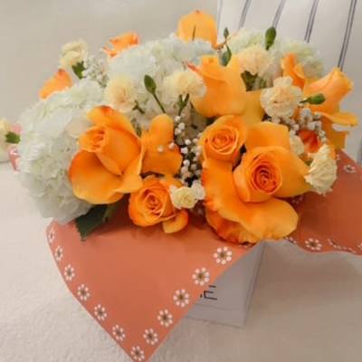 Orange roses and white flowers in a wrapped bouquet