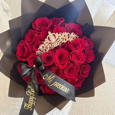 Bouquet of red roses wrapped in black paper with a tiara and ribbon