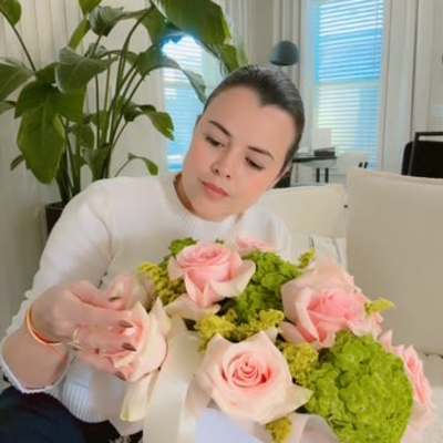 Woman holding a bouquet of pink roses and green hydrangeas in a white box