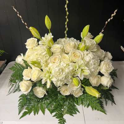 White roses and lilies arranged with hydrangeas in a low centerpiece
