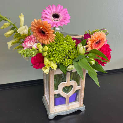 Colorful mixed flower arrangement in a wooden lantern-style container