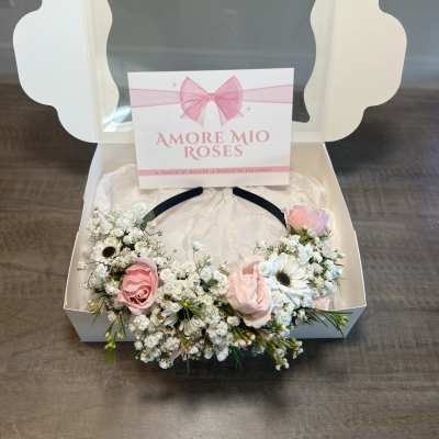 Pink roses and white daisies arranged in a gift box with a ribbon card