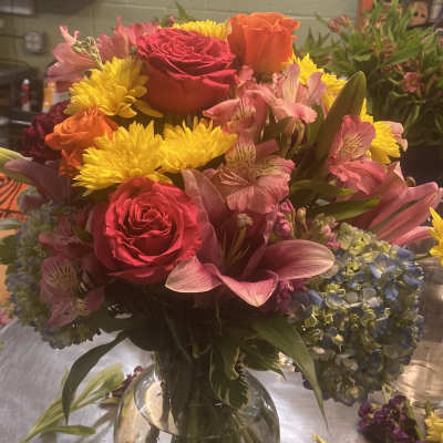 Mixed bouquet of roses, lilies, chrysanthemums, and hydrangeas in a glass vase
