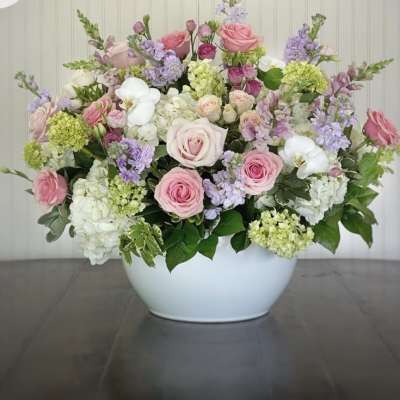 Large pastel flower arrangement in a white bowl vase