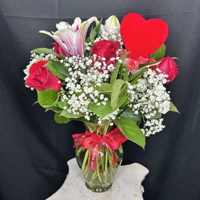 Bouquet of red roses and white lilies in a glass vase with a red heart pick