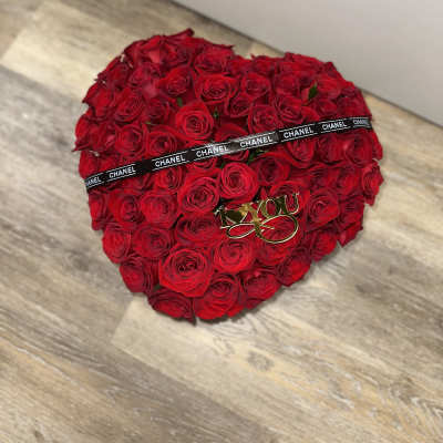 Heart-shaped bouquet of red roses with a black ribbon and gold "I love you" topper