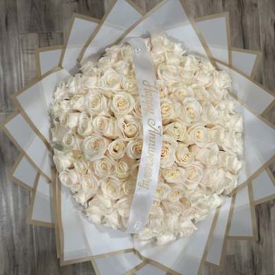 Large bouquet of cream roses wrapped in white paper with a ribbon