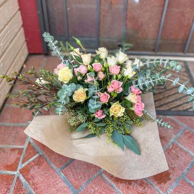 Bouquet of pink and cream roses with eucalyptus in kraft paper